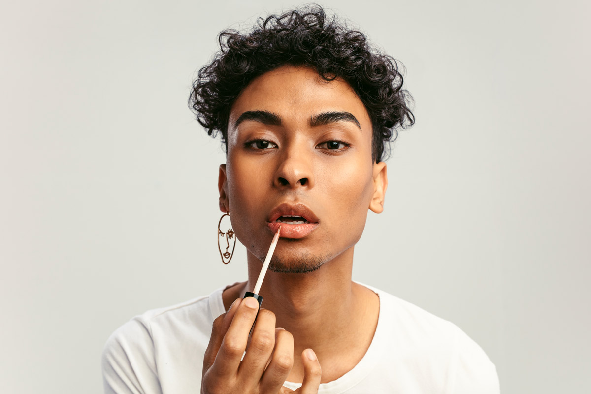 A man puts on lipgloss. 