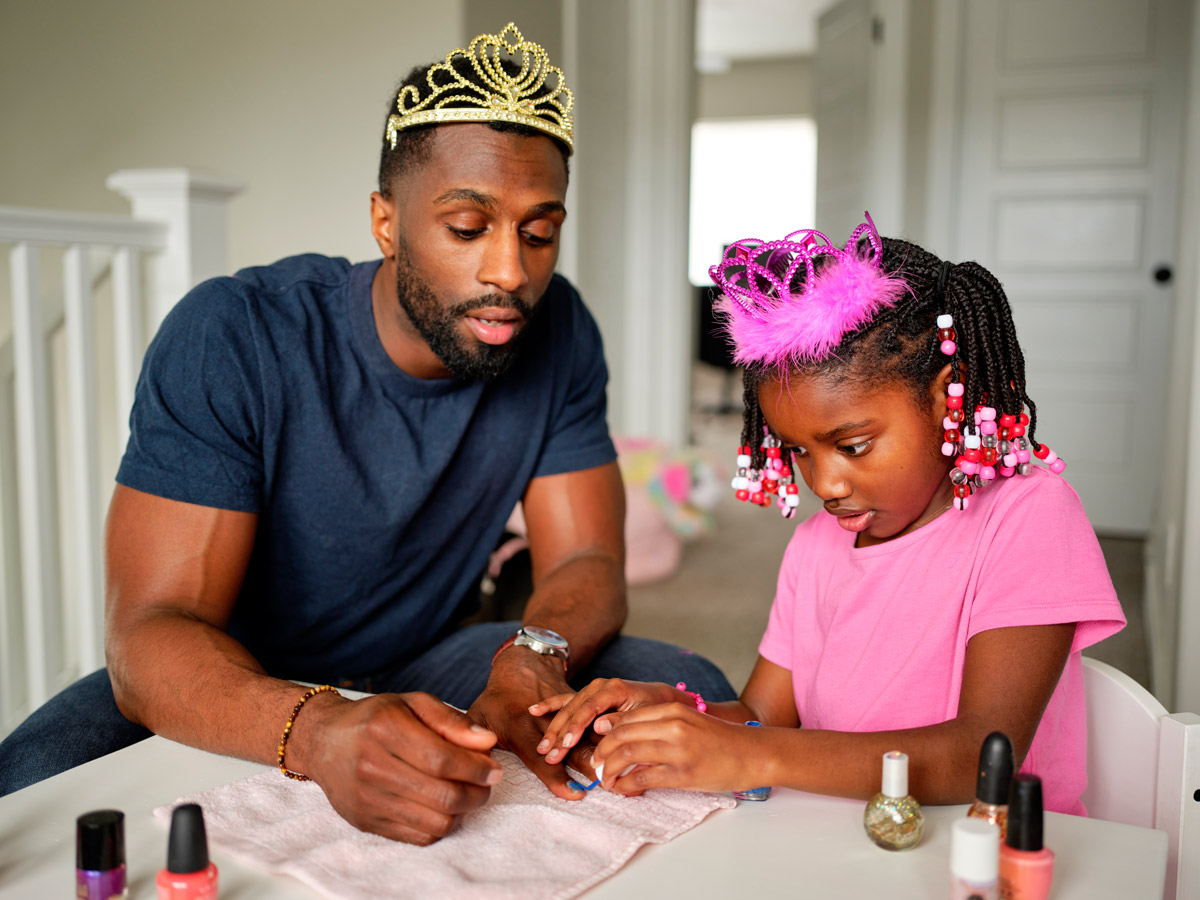 A father and daughter paint their nails. 