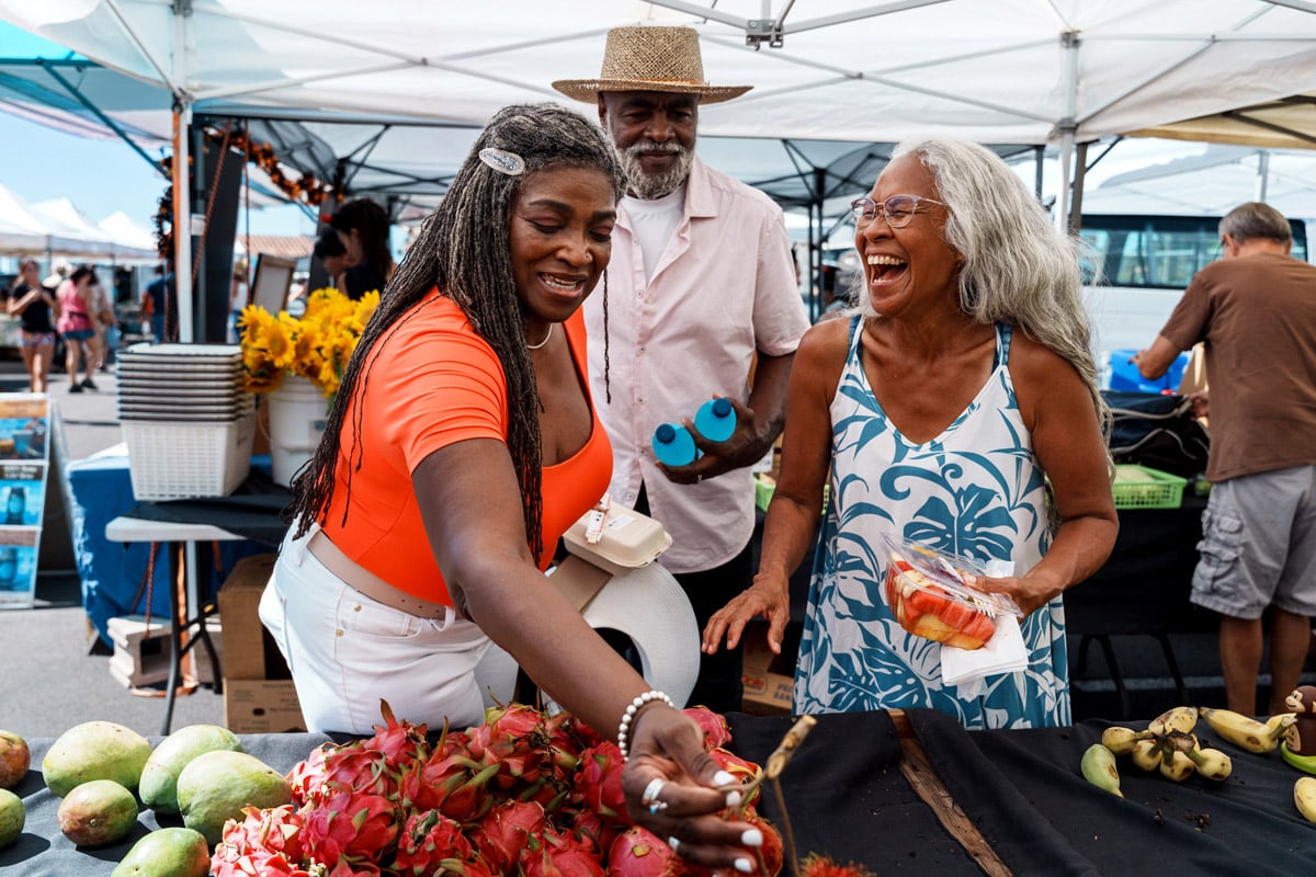 A group of three people laugh as they shot at a farmer's market.