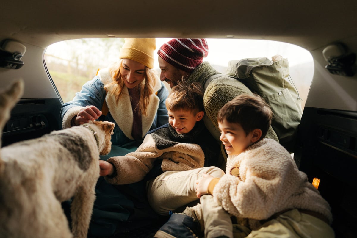 A family gets ready for a road trip in their vehicle.