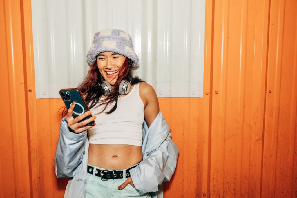 A woman smiles as she looks at her phone.