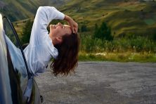 A woman hangs out the front window letting the wind in her hair.