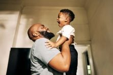 A father lifts his son into the air as they play together.