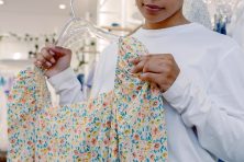 A woman looks at a floral blouse inside a store.