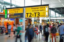 Airline passengers walk through a busy corridor of an airport.