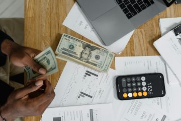Person calculating their monthly expenses and income using paper and calculator