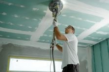 A man does a home renovation to his ceiling.