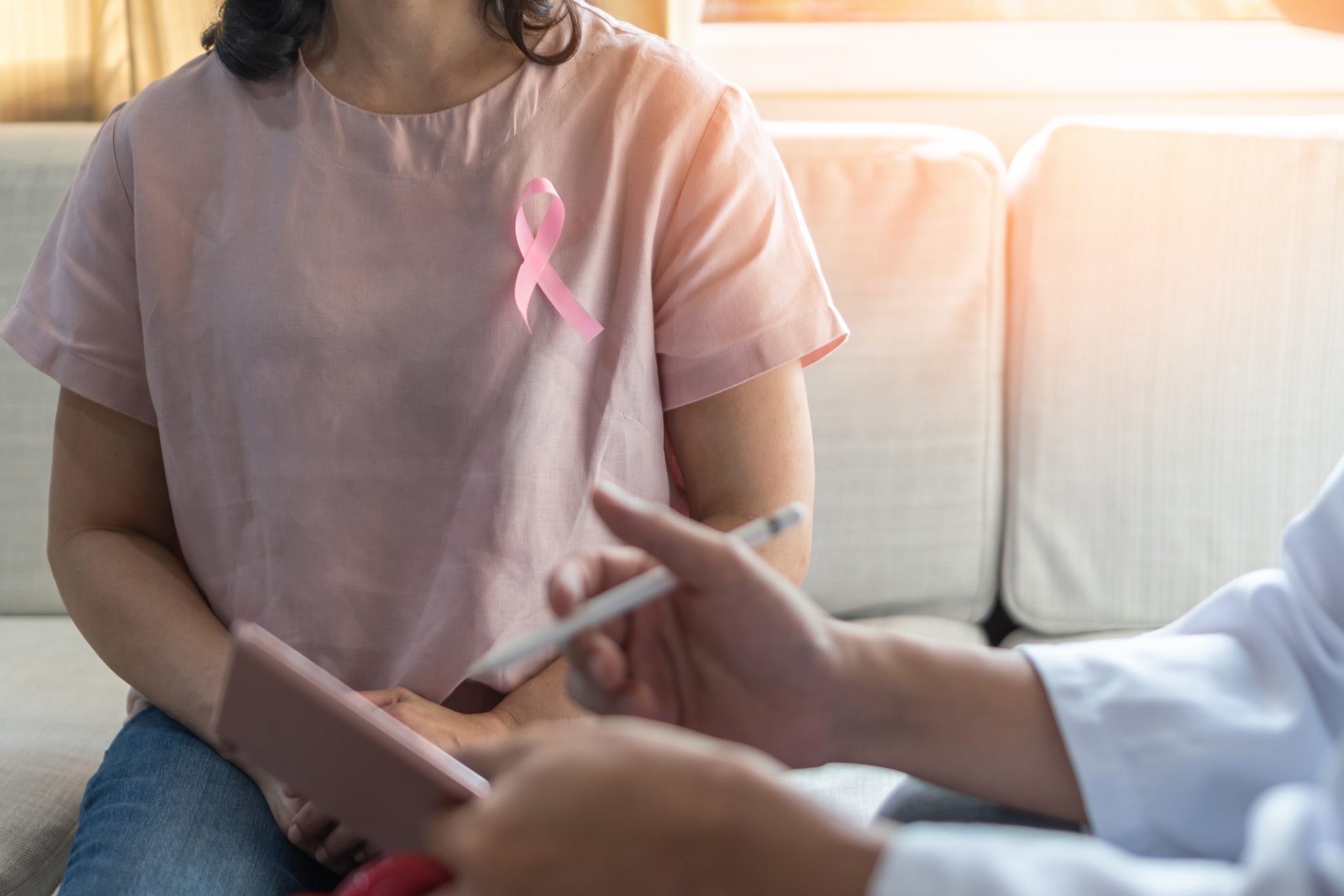 Breast cancer pink awareness ribbon on woman patient consulting with doctor