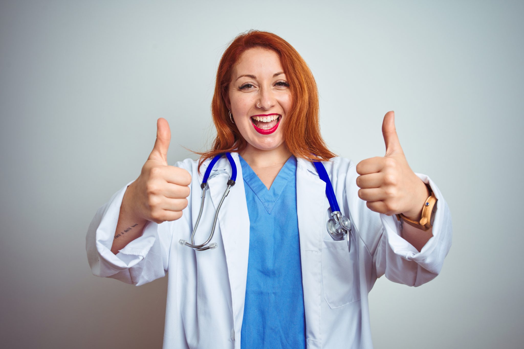 Young doctor woman wearing stethoscope over white isolated background with thumbs up smiling and happy.