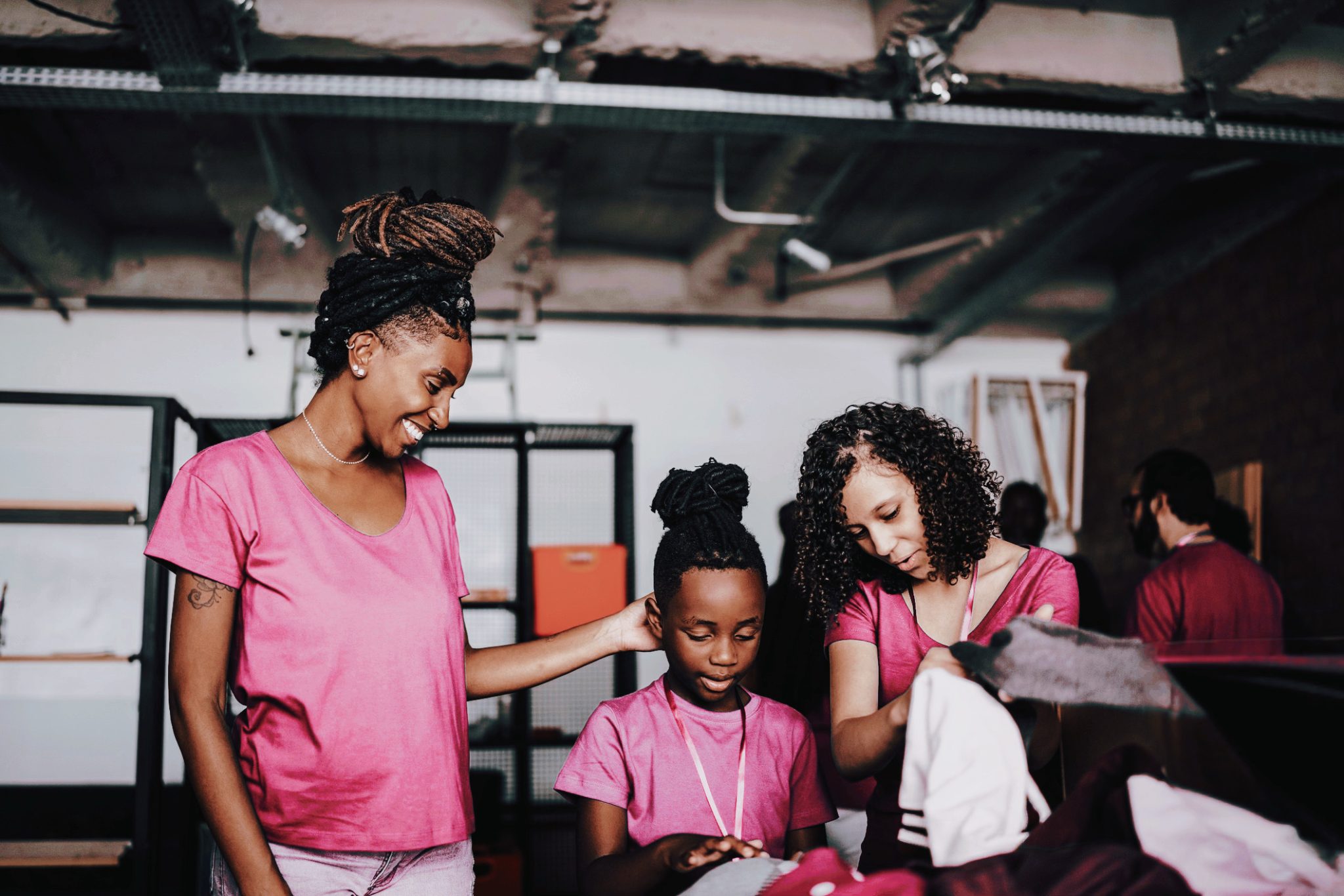 ethnic women wearing pink and working together in community