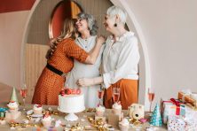 A woman is hugged by friends on her 60th birthday.