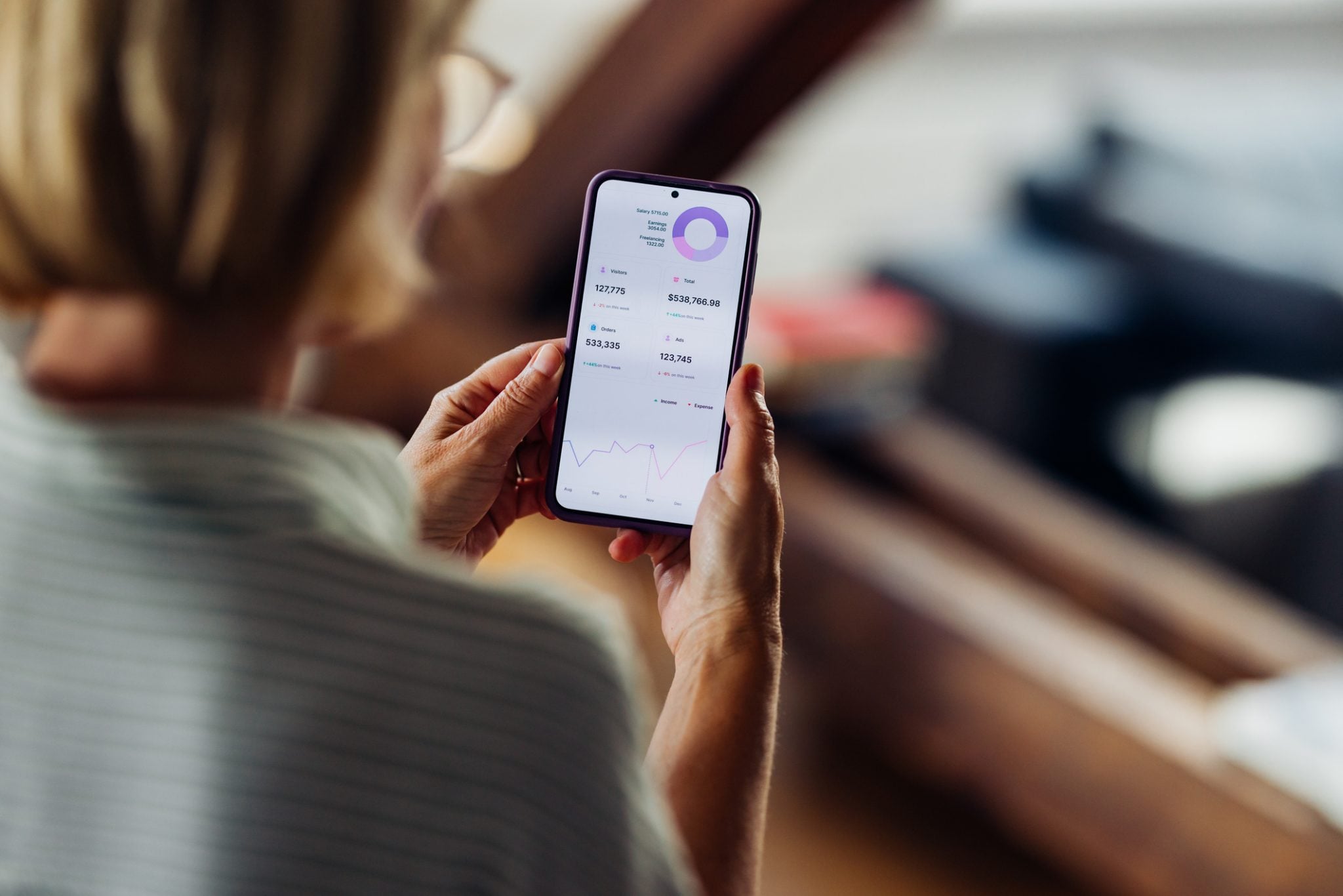 Woman Analyzing Financial Data on Smartphone at Home