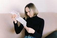 A woman looks at a pile of receipts.