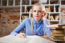 A college student takes a pause from her reading during a study session in a library setting.