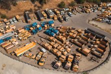 Surplus industrial trucks and vehicles are stored on a fenced lot.