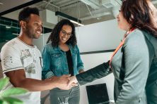 A financial therapist shakes hands with a couple during a consultation.