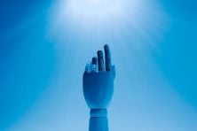 A robot hand reaches up toward the blue sky.