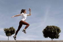 A woman leaps while running outside.