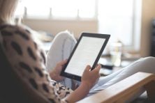 A woman reads on a tablet.