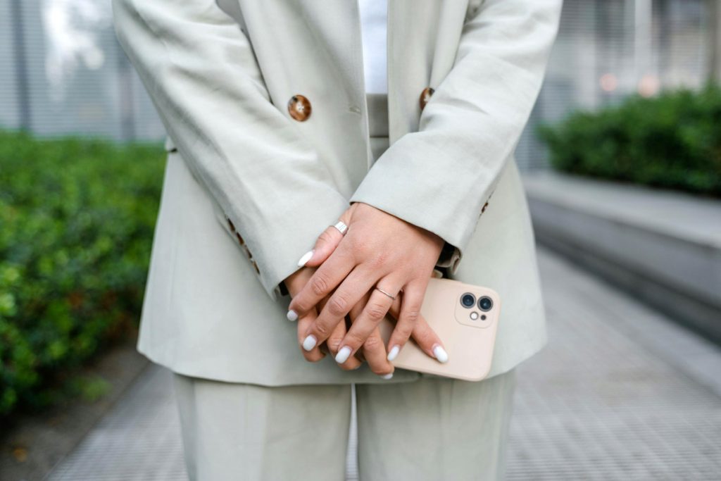 A woman in a business suit holds a phone.