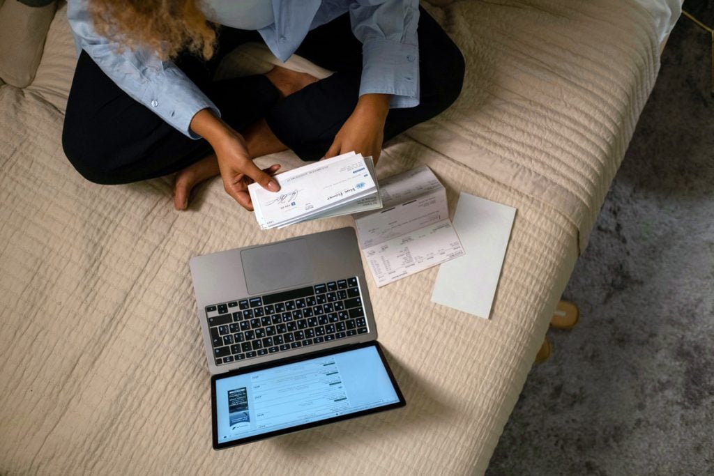 A woman looks over her bills with her laptop open.