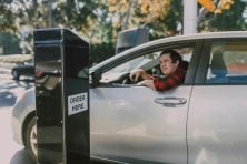 A man orders food from his car at a drive through.