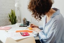 Person organizing their finances with a budget planner, budgeting app and sticky notes
