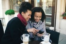Parent teaching child to use a financial literacy app on a smartphone to learn about money management
