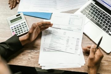 Person reviewing their monthly expenses and taking notes to improve their budget