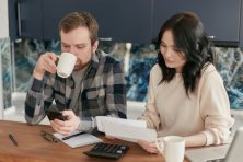 Two people discuss bills while sitting at a table.