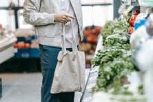 Someone stands in front of produce at a grocery store.