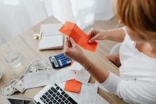 A woman looks at a receipt while sitting at a desk and working on a budget.