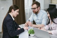 A man and a woman talk with someone about a loan application.